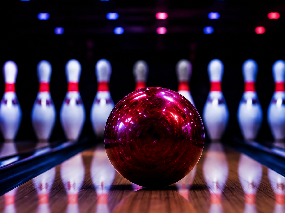 Bowling ball lined up with illuminated pins at the end of a lane